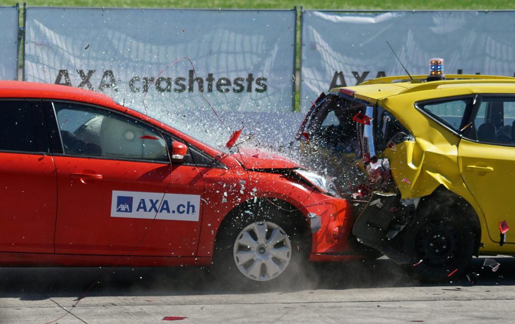 Red and yellow cars shown in a head-on collision during a crash test for safety evaluation.